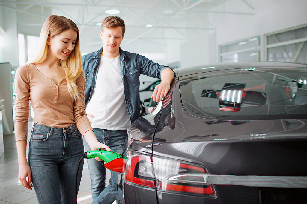 Couple shopping for an electric vehicle. She's charging it.