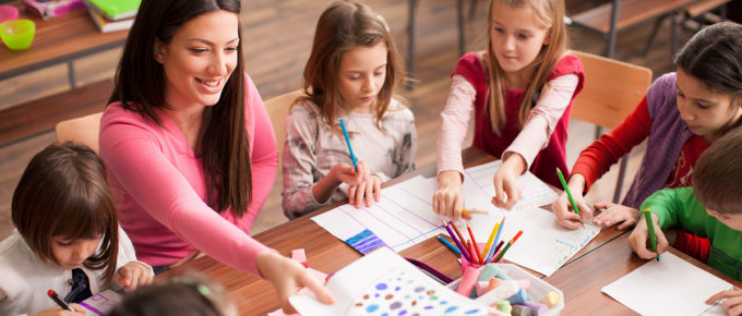 Teacher at a table with elementary school children.