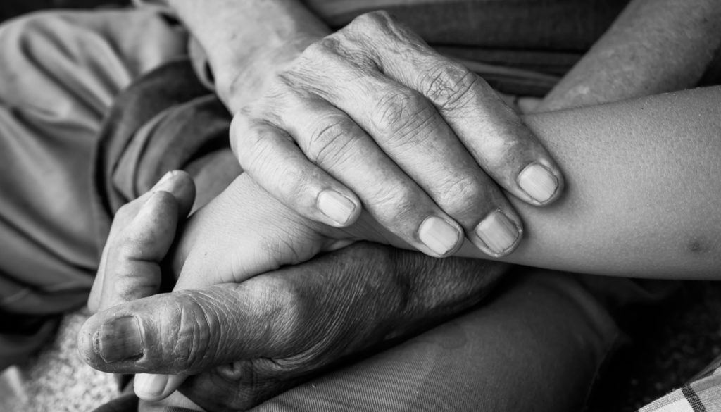 kids little boy hand touches and holds an old man wrinkled hands.