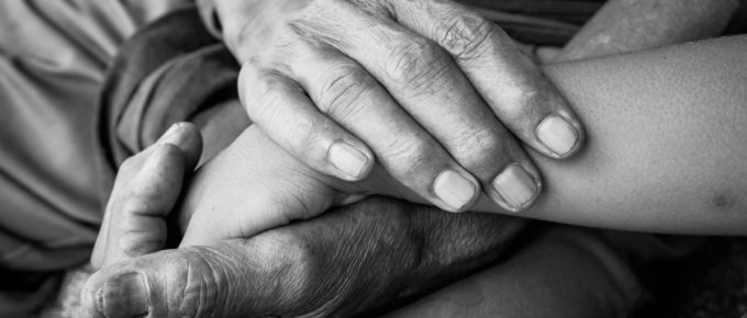 kids little boy hand touches and holds an old man wrinkled hands.