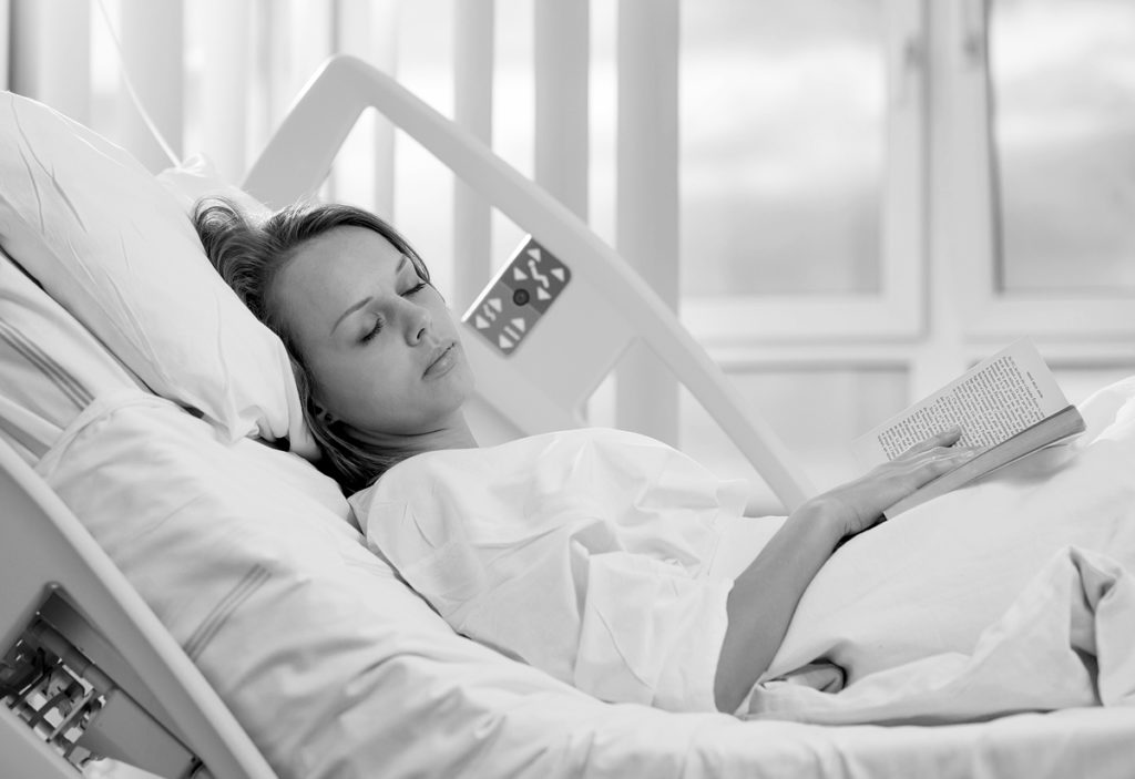 Teenage girl lying in hospital bed.