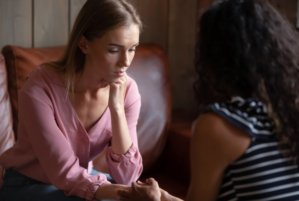 Depressed woman visiting psychologist, talking about problems, African American counselor therapist holding patient hands, comforting, expressing understanding and empathy, personal therapy session 