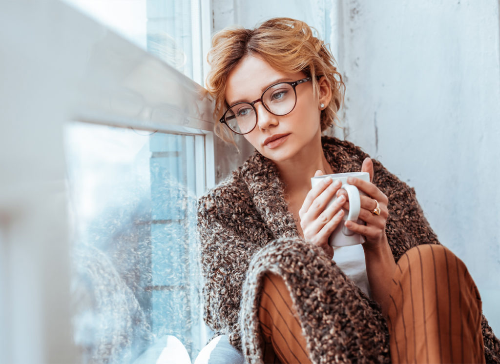 Girl feeling sad and alone leaning against window