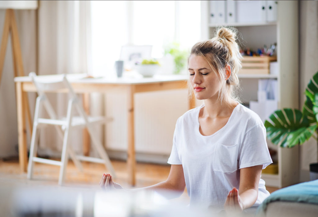 Woman meditating in living room. Morning routines.