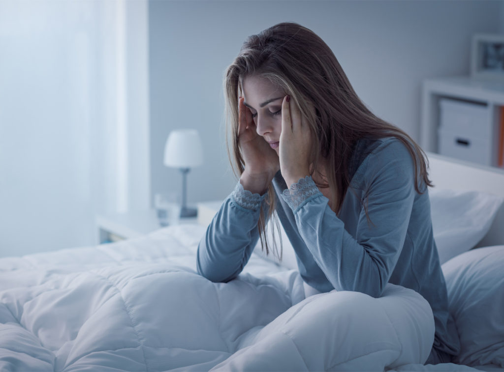 Woman in bed feeling stressed and anxious.