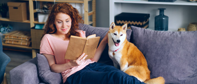 Young woman on sofa with Shiba Inu. Best dog for apartment.