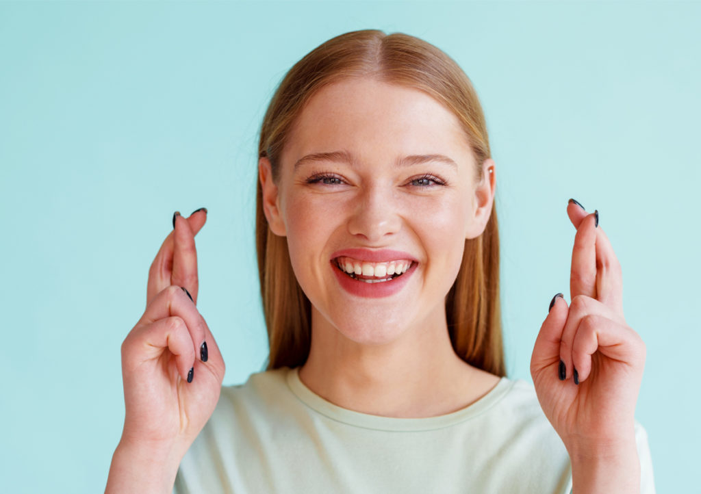 woman smiling and crossing fingers for good luck