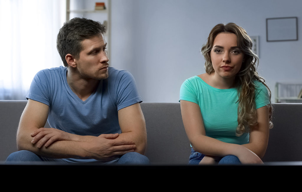 Couple on sofa, emotionally disconnected. Husband and wife.